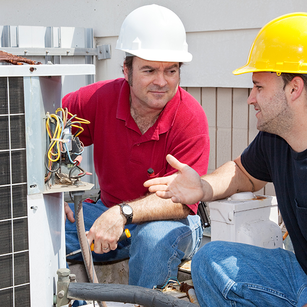 Residential HVAC technician training his HVAC helper perform preventive maintenance