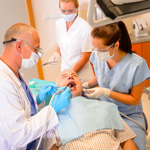 Two dental assistants making the patient comfortable in the chair 