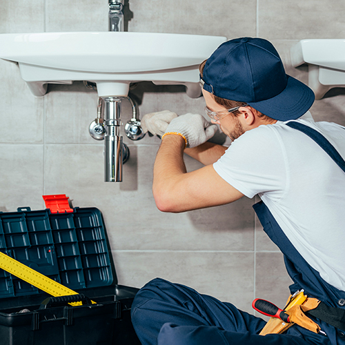 Plumber installing pipes and fixtures on sinks for water, gas, steam, and air