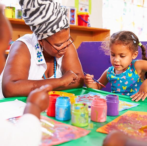 Preschool teacher teaching basic skills such as colors and shapes to little girl