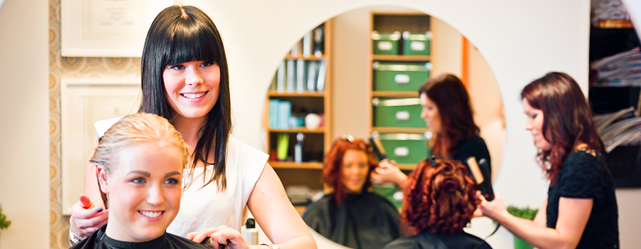 Cosmetologist conversing with client to cut, style, and color hair