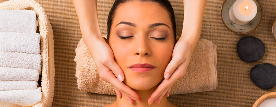 Facial specialist cleaning client’s skin before applying lotion