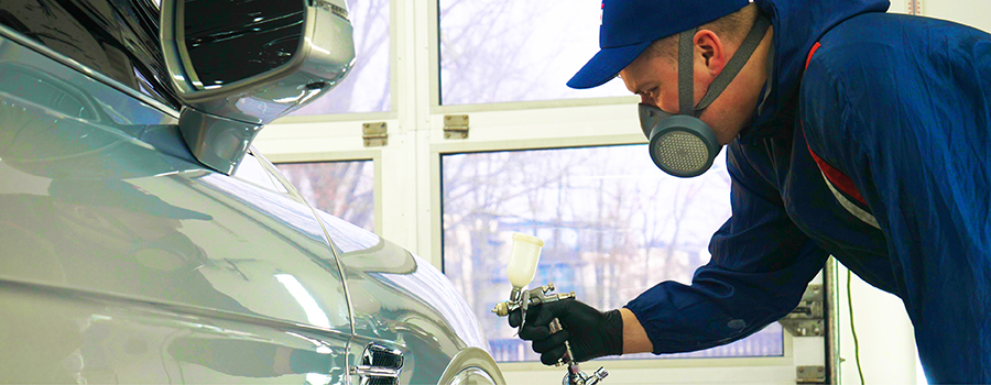 Repairman sanding plastic car bumper