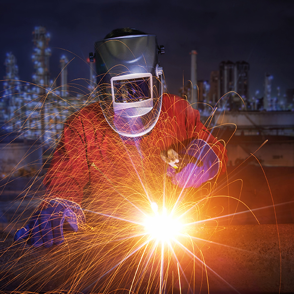 Worker with protective mask welding metal and sparks 
